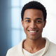 A happy young adult, smiling, against a soft slate blue and white background.